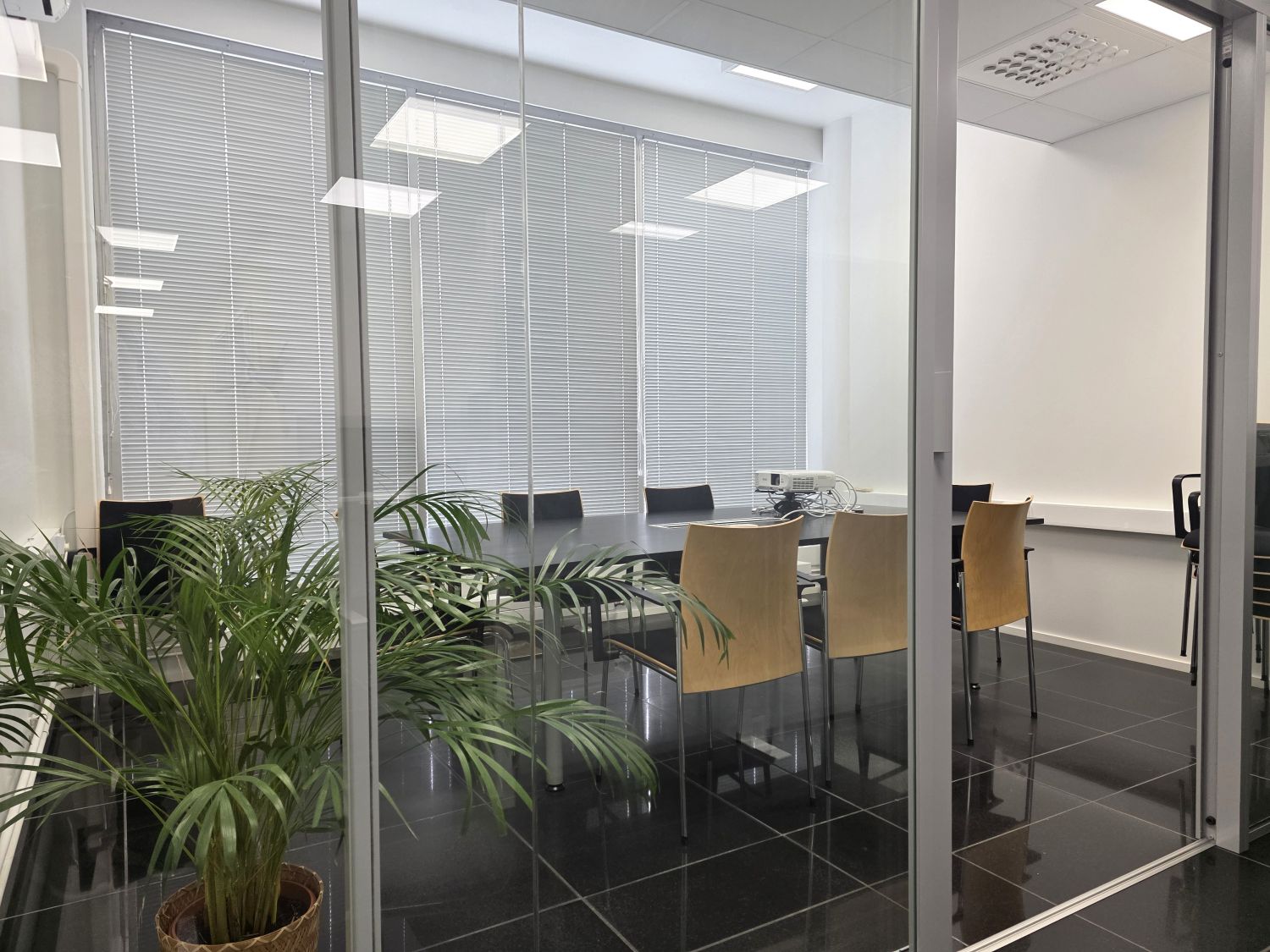 Lasiseinäinen neuvottelutila, näkymä sisäpihalle