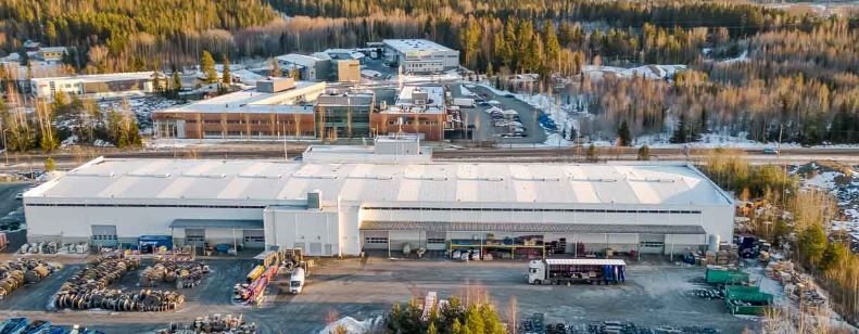 Ilmakuva teollisuusalueesta ja sen rakennuksista metsäisessä maisemassa.