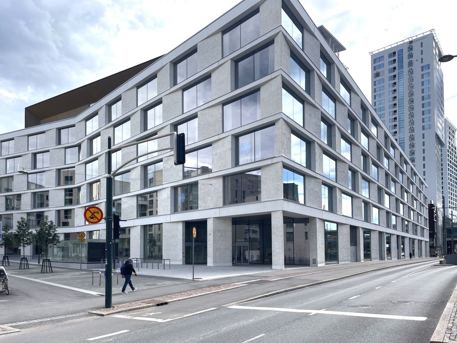 Moderni vaalea rakennus kadun kulmassa kaupunkiympäristössä.