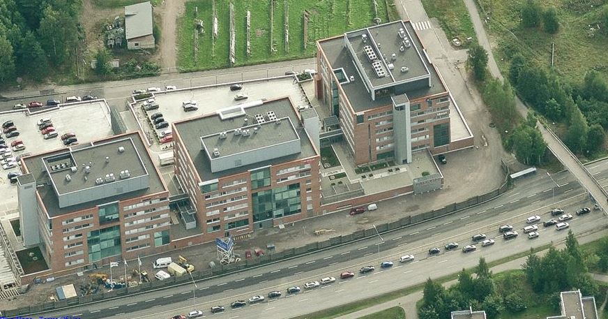 Ilmakuva kolmesta toimistorakennuksesta ja niiden vieressä kulkevasta vilkkaasta tiestä.