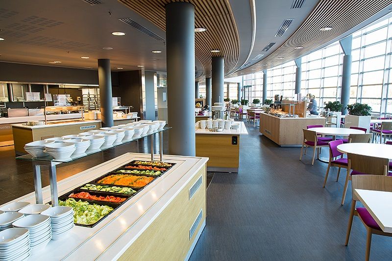 Valoisa ja moderni ravintolasali, jossa on salaattipöytä.
