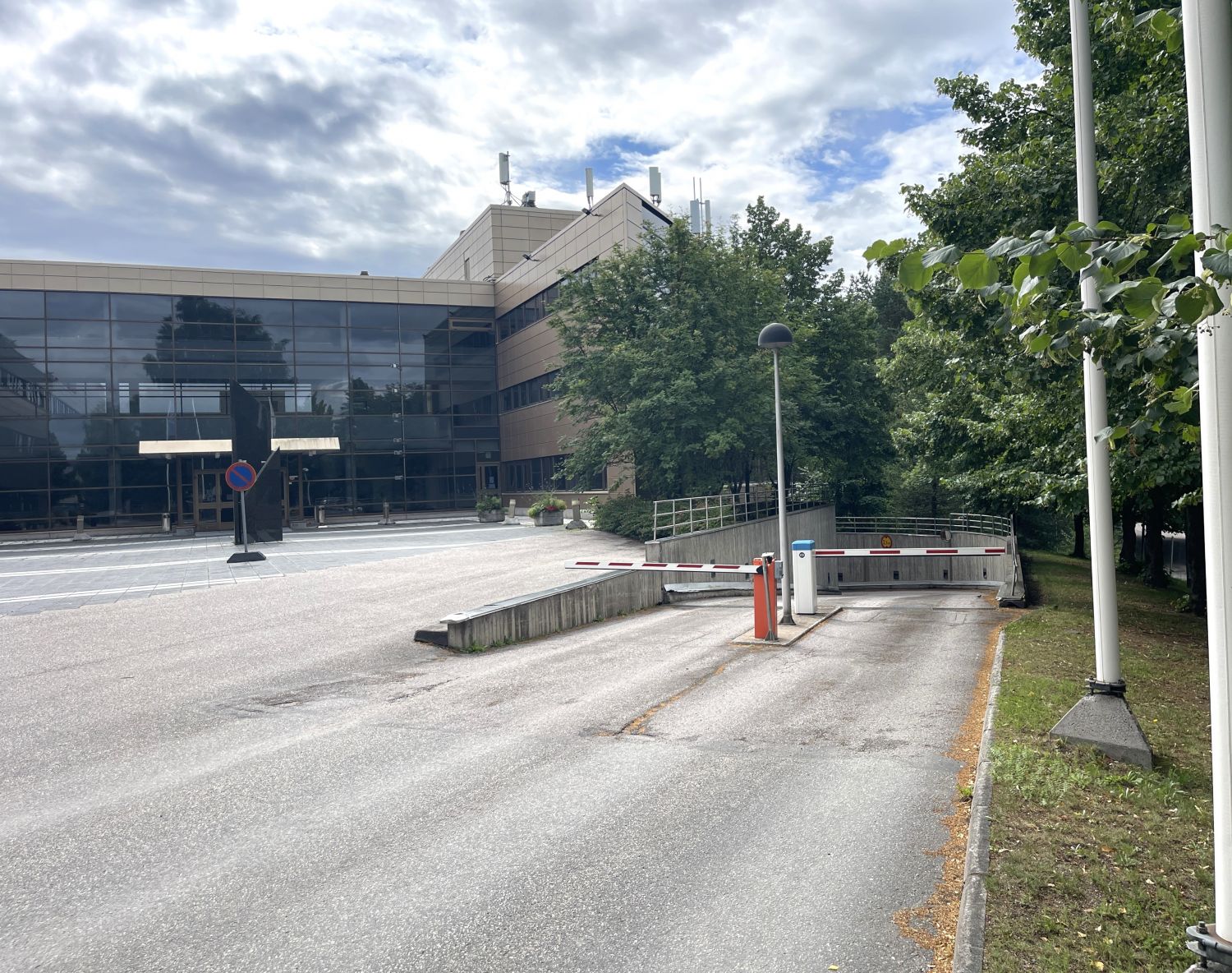 Moderni toimistorakennus ja maanalaisen pysäköintihallin sisäänkäynti puomeineen.