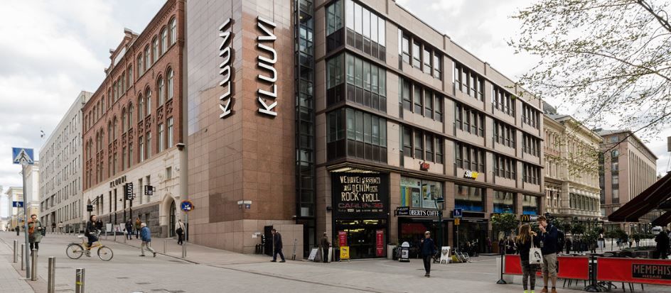 Katunäkymä Helsingistä, jossa näkyy Kluuvin kauppakeskus ja ohikulkijoita.