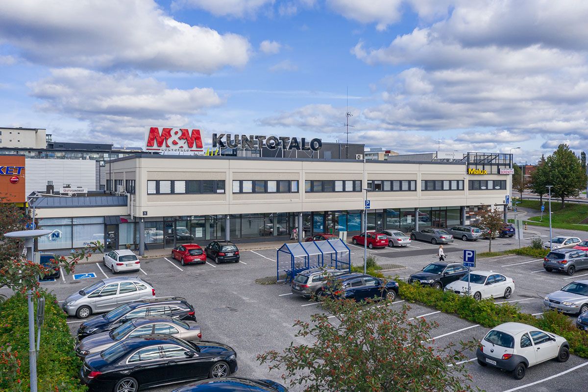 Liikerakennus ja sen edustalla oleva pysäköintialue autoineen.