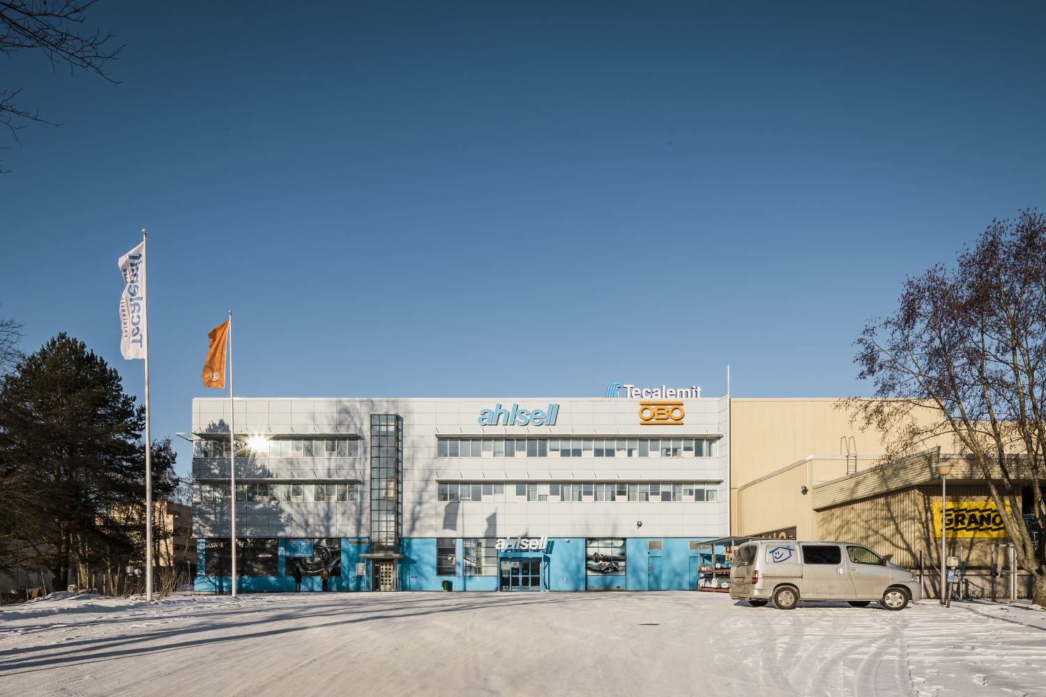 Toimisto- ja teollisuusrakennus lumisella pihalla aurinkoisena talvipäivänä.