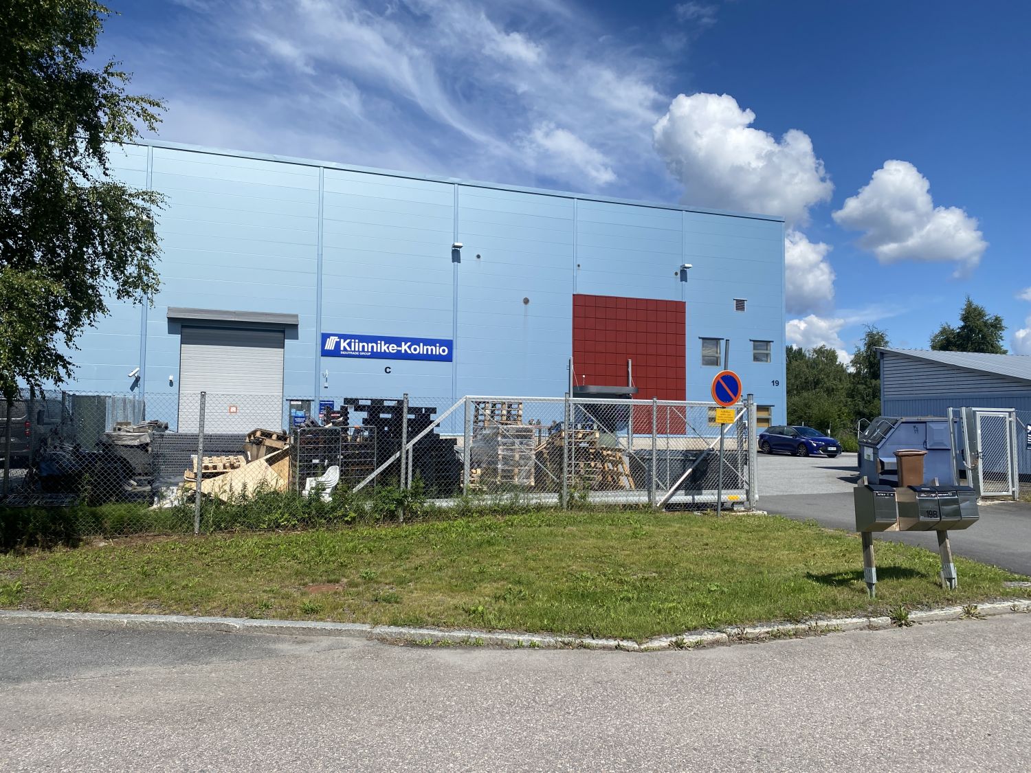 Kiinnike-Kolmion vaaleansininen teollisuusrakennus ja aidattu piha-alue.