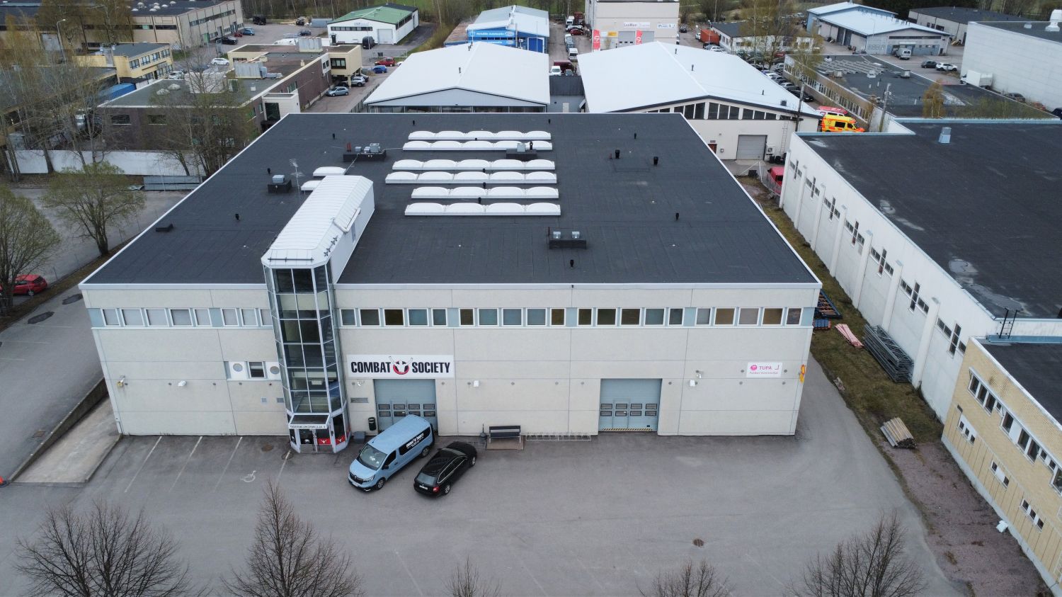 Ilmakuva vaaleasta liikerakennuksesta, jonka seinässä lukee Combat Society.