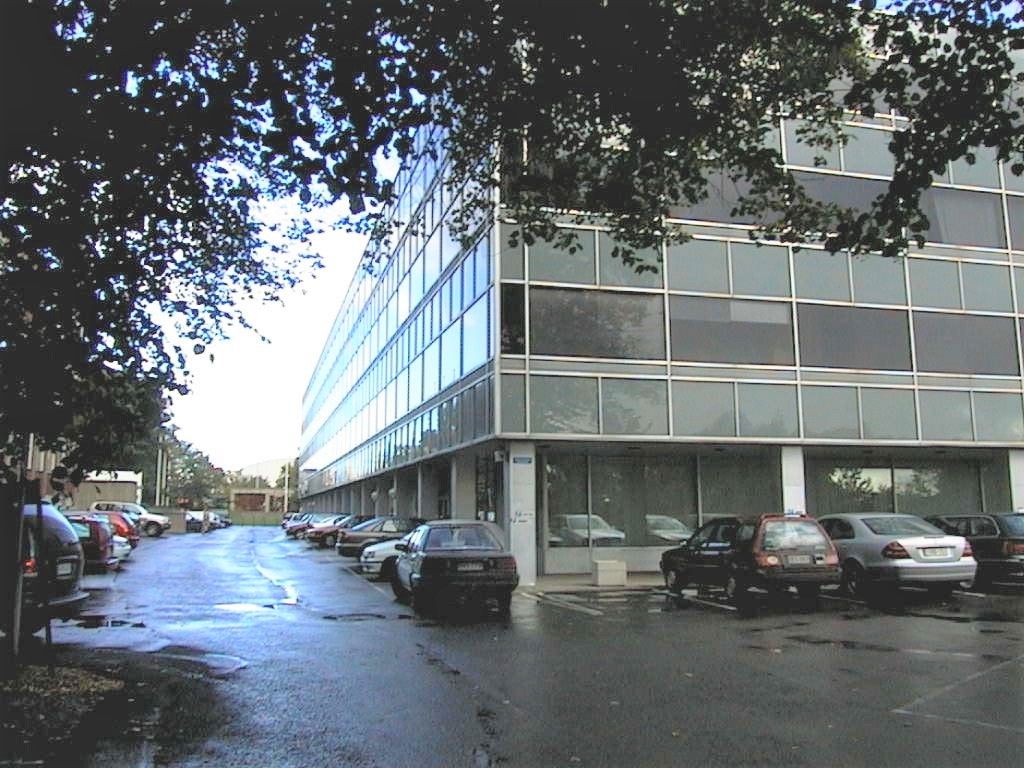 Moderni toimistorakennus ja sen edustalla oleva parkkipaikka.