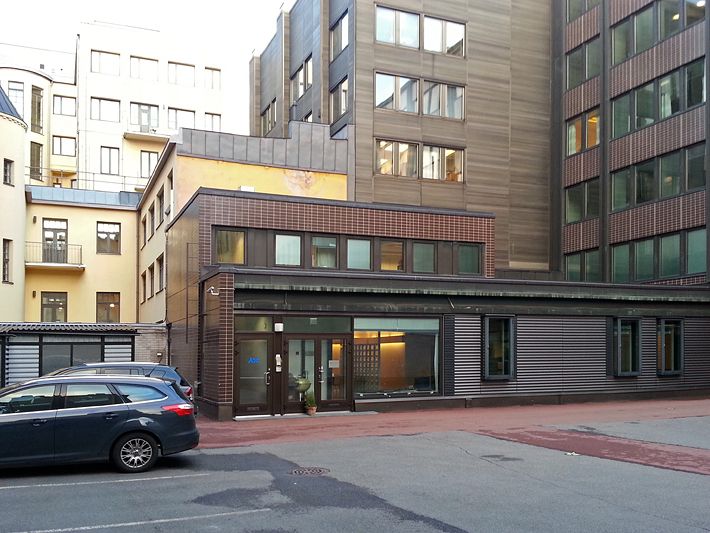 Näkymä rakennusten väliselle pihalle, jossa on pysäköity auto.