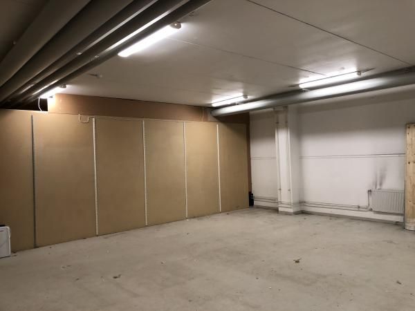 Tyhjä varastotila, jossa on ruskeat seinäpaneelit ja loisteputkivalaistus.