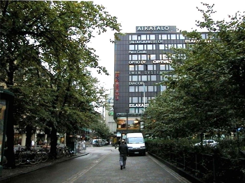 Näkymä puiden reunustamalta kävelykadulta, jonka taustalla on Aikatalo-rakennus.
