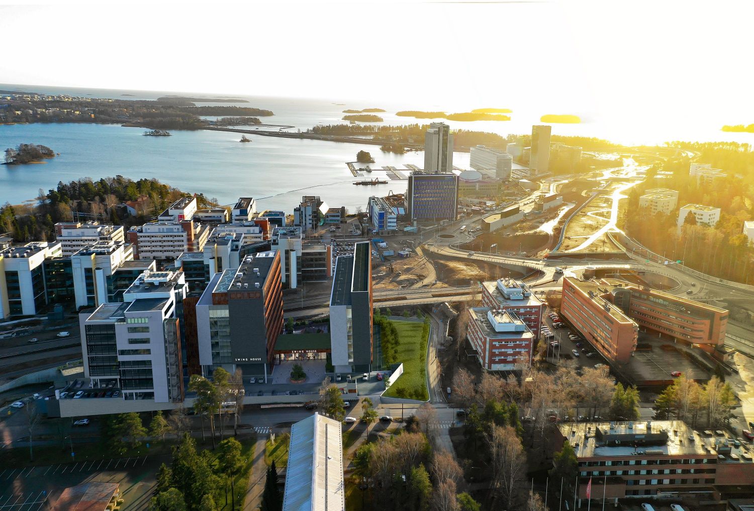 Ilmakuva modernista kaupunkialueesta meren rannalla auringonlaskun aikaan.