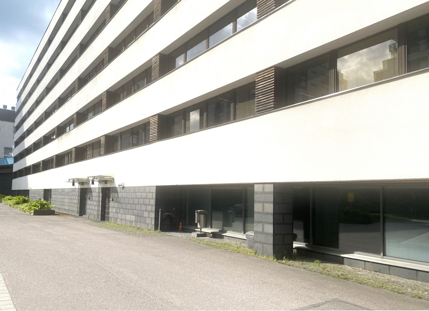 Moderni monikerroksinen valkoinen rakennus, jossa on useita vaakasuuntaisia ikkunarivejä.