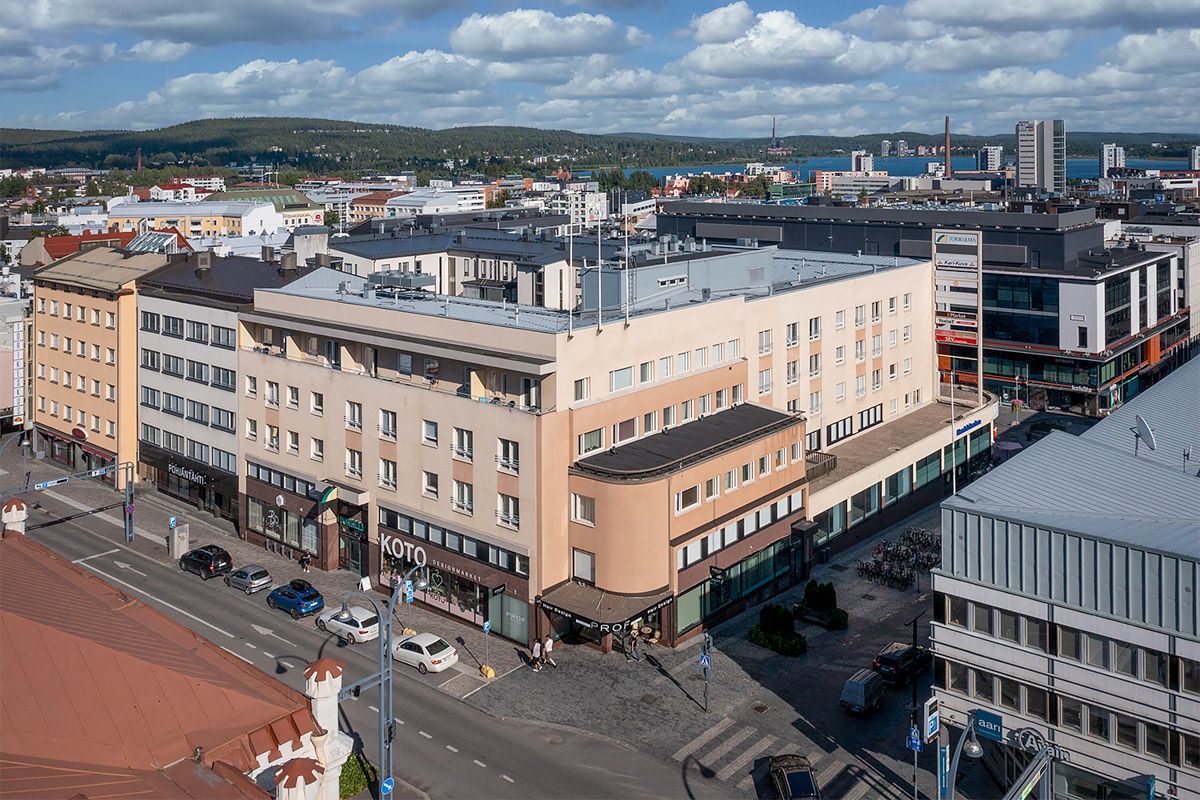 Korkealta otettu näkymä kaupungin keskustaan, jossa on asuin- ja liikerakennuksia, katuja ja taus...