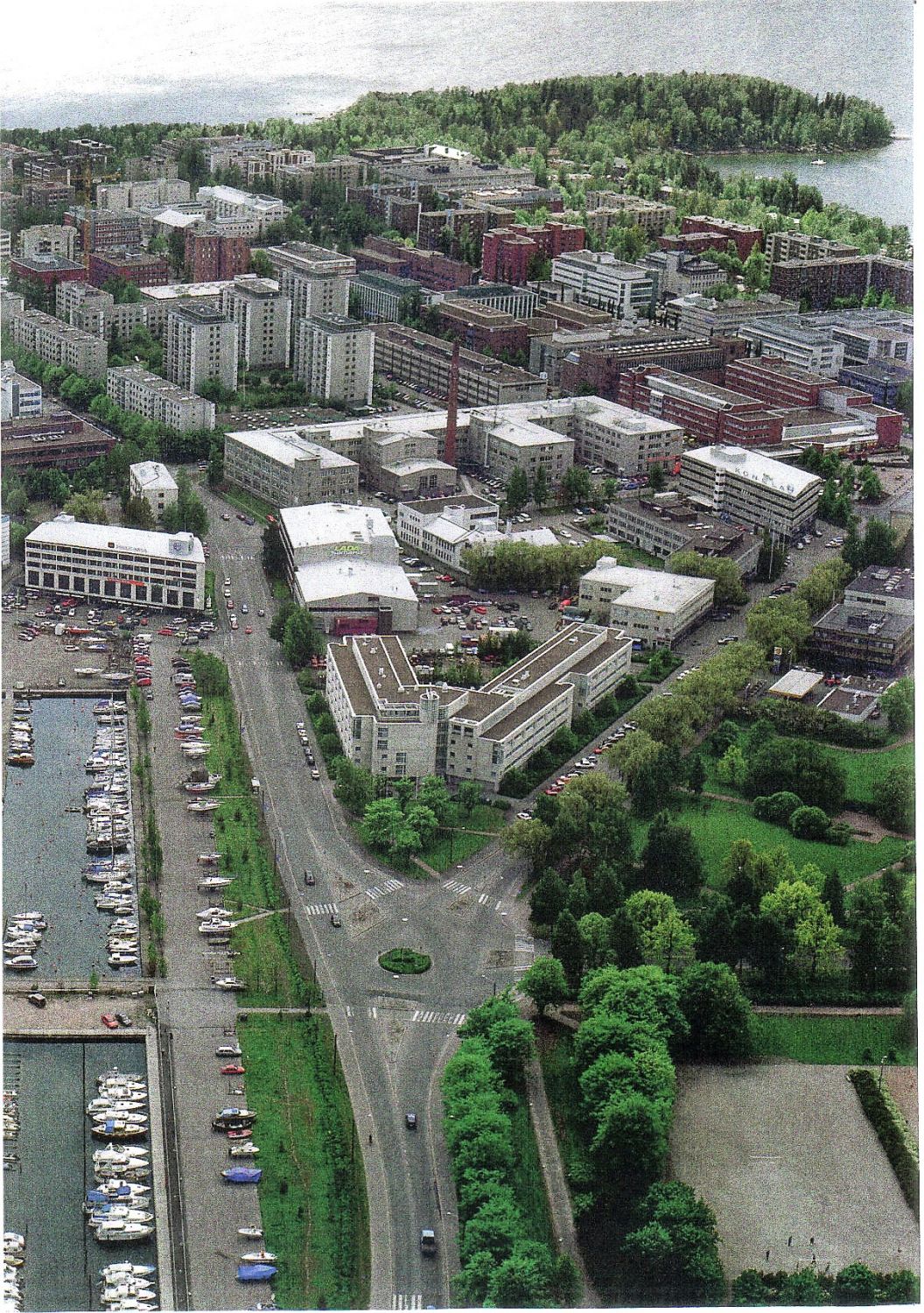 Ilmakuva kaupunkimaisemasta, jossa on satama-allas veneineen, puistoalueita, katuja ja monenlaisi...