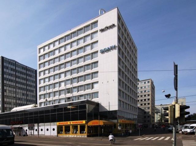 Valkoinen monikerroksinen liikerakennus kaupunkiympäristössä.