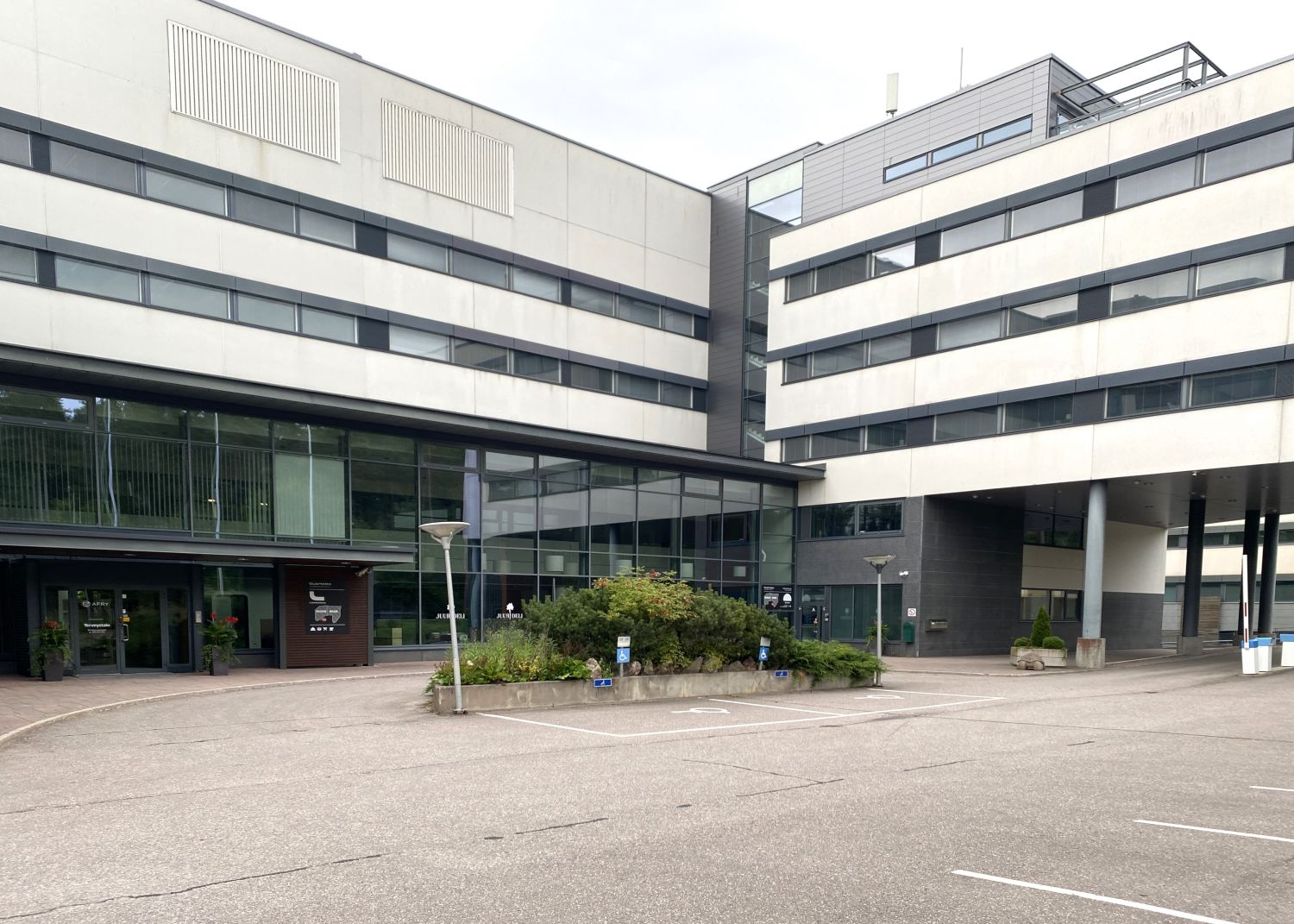 Moderni toimistorakennus ja sen edustalla oleva piha-alue istutuksineen.