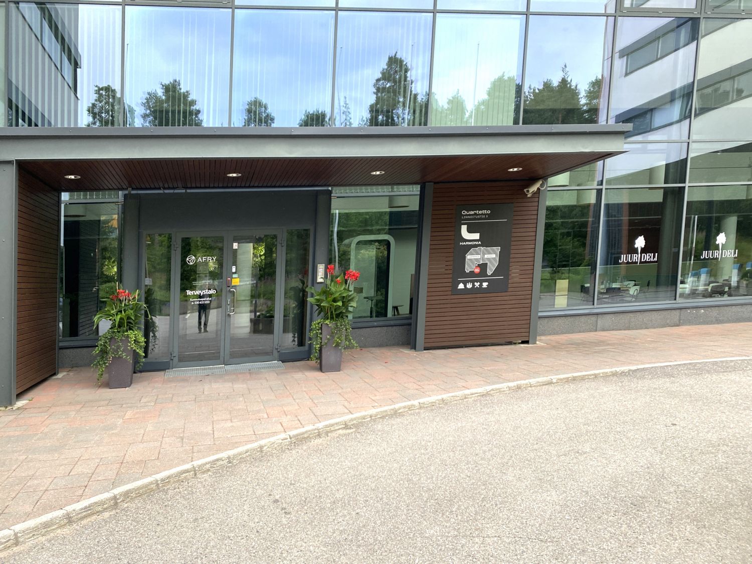 Modernin toimistorakennuksen sisäänkäynti, jossa on lasiovet ja yritysten opasteita.
