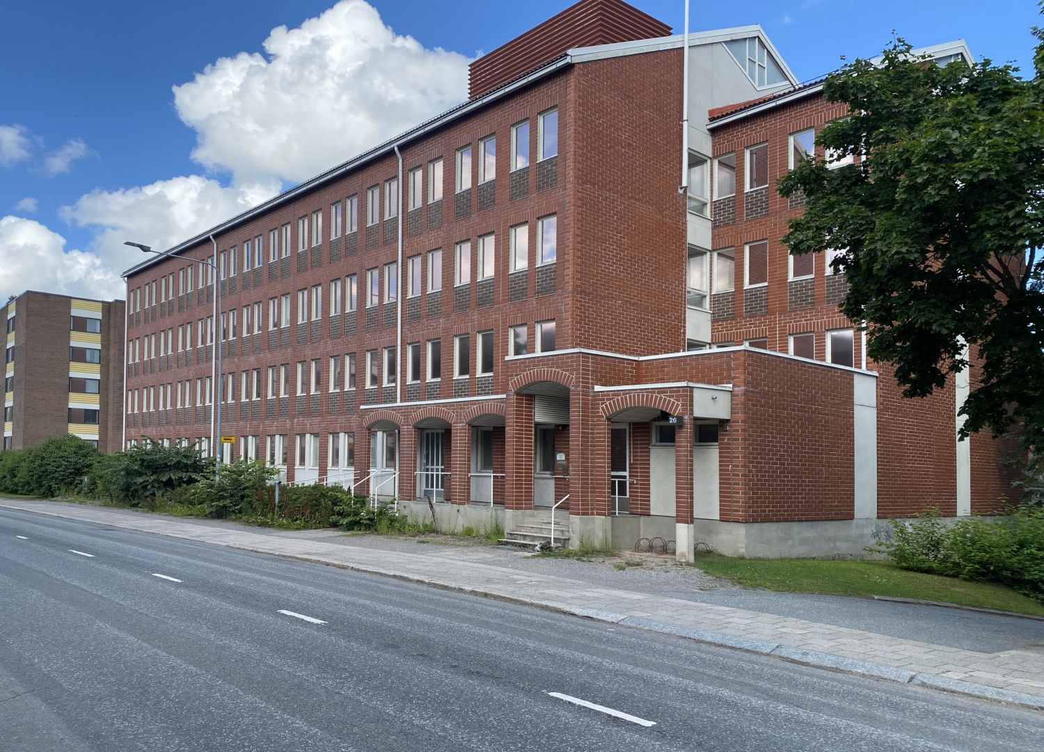 Punatiilinen kerrostalo kadun varrella aurinkoisena päivänä.