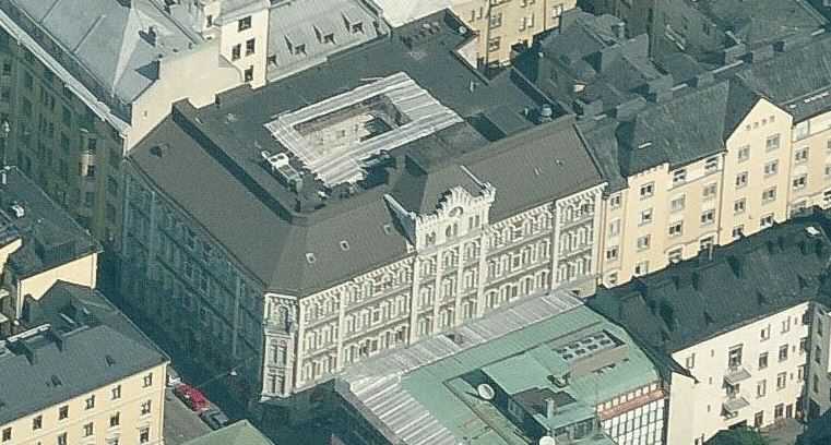Ilmakuva vanhasta koristeellisesta rakennuksesta tiiviissä kaupunkiympäristössä.