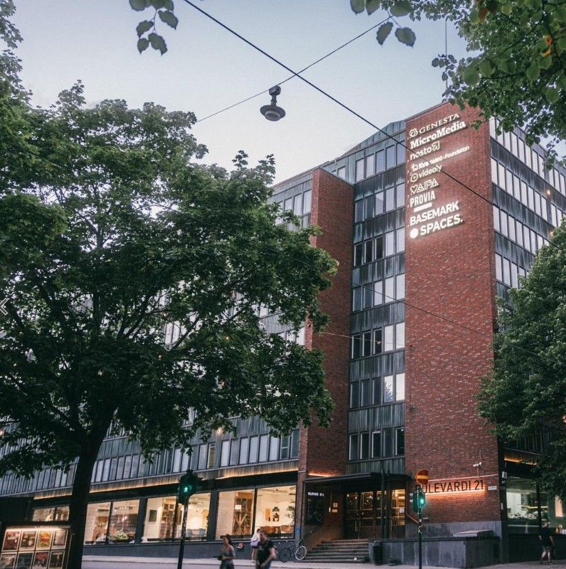 Tiilinen toimistorakennus puiden katveessa kaupunkimiljöössä.
