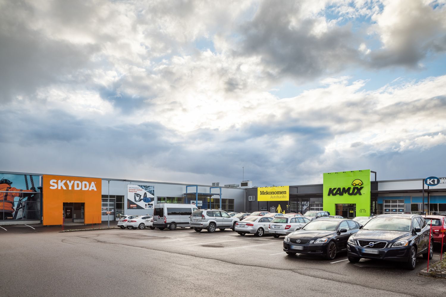 Liikerakennus ja pysäköintialue, jossa sijaitsevat Skydda-, Mekonomen- ja Kamux-liikkeet.
