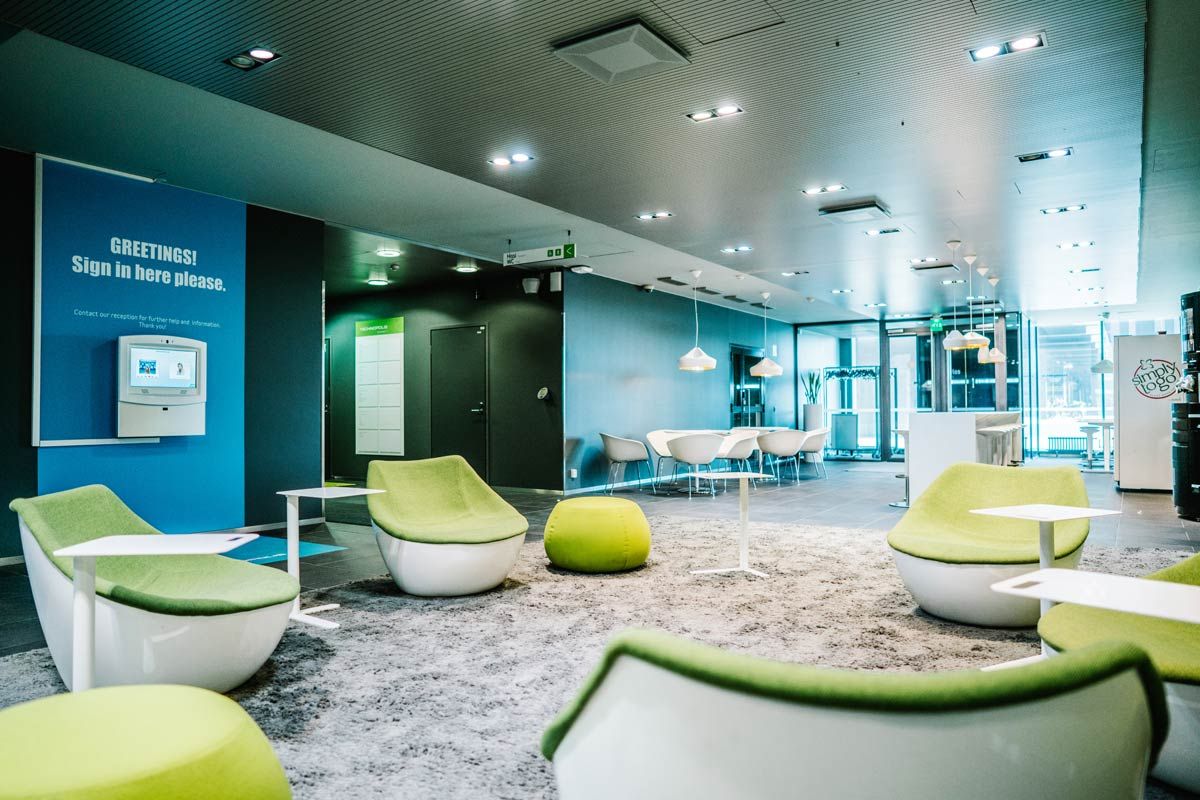 Moderni ja valoisa aulatila, jossa on vihreitä nojatuoleja.