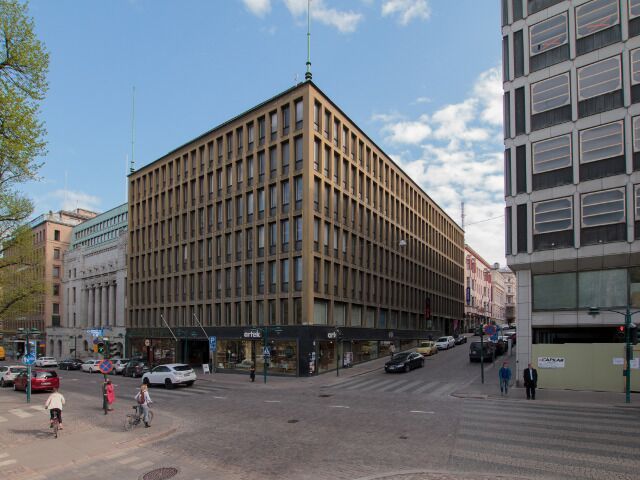 Kaupunkinäkymä, jossa on suuri liikerakennus katuristeyksessä.
