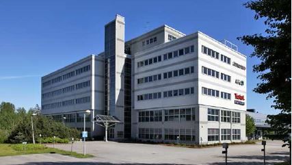 Valkoinen monikerroksinen toimistorakennus aurinkoisena päivänä.