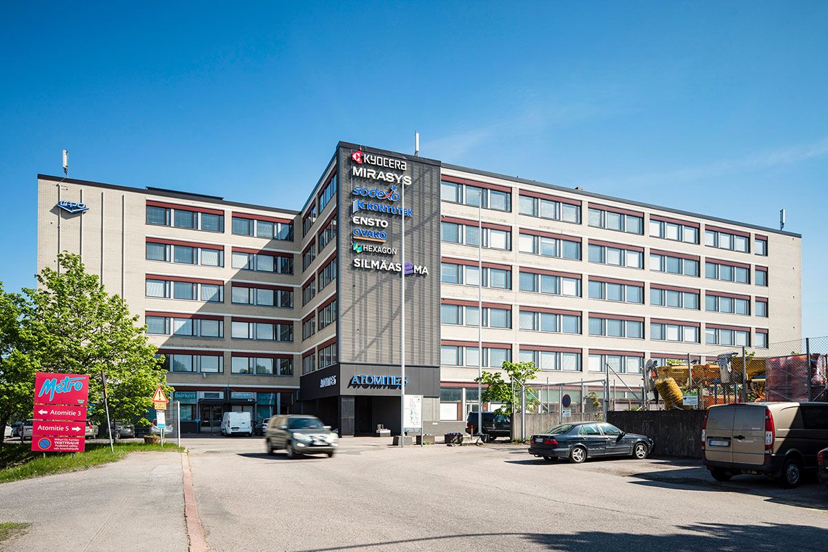 Näkymä monikerroksisesta toimistorakennuksesta, jonka julkisivussa on useita yrityslogoja.