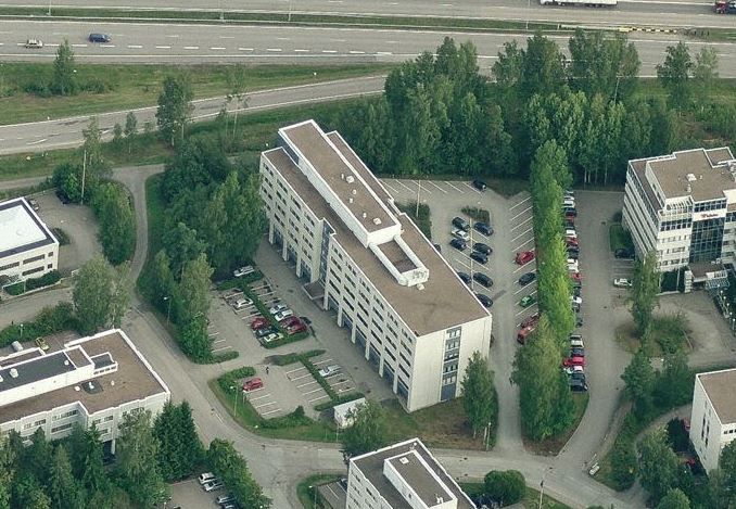 Ilmakuva toimistorakennuksista, pysäköintialueista ja ympäröivästä puustosta.