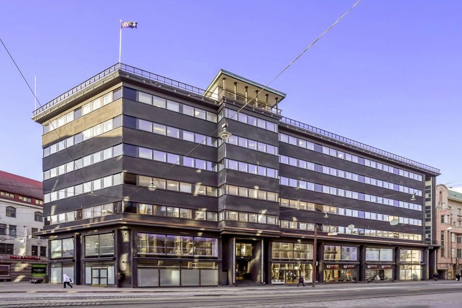 Tumma funktionalistinen rakennus kaupunkiympäristössä.