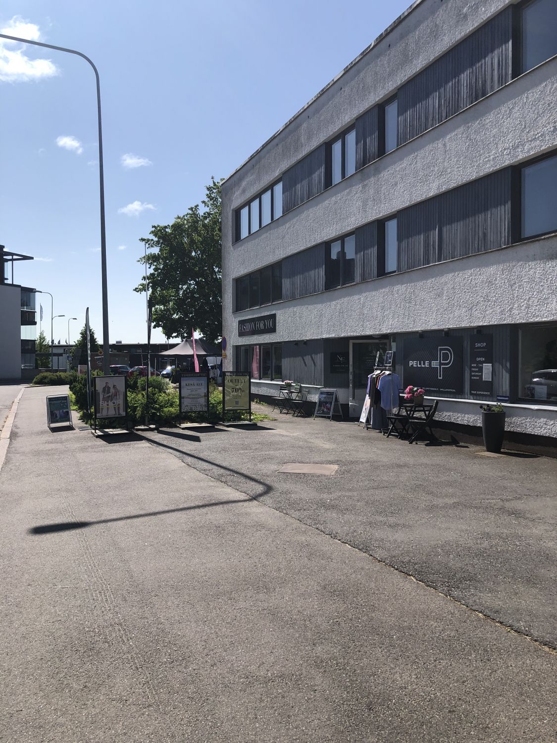 Liikerakennus ja vaateliikkeiden sisäänkäyntejä aurinkoisena päivänä.