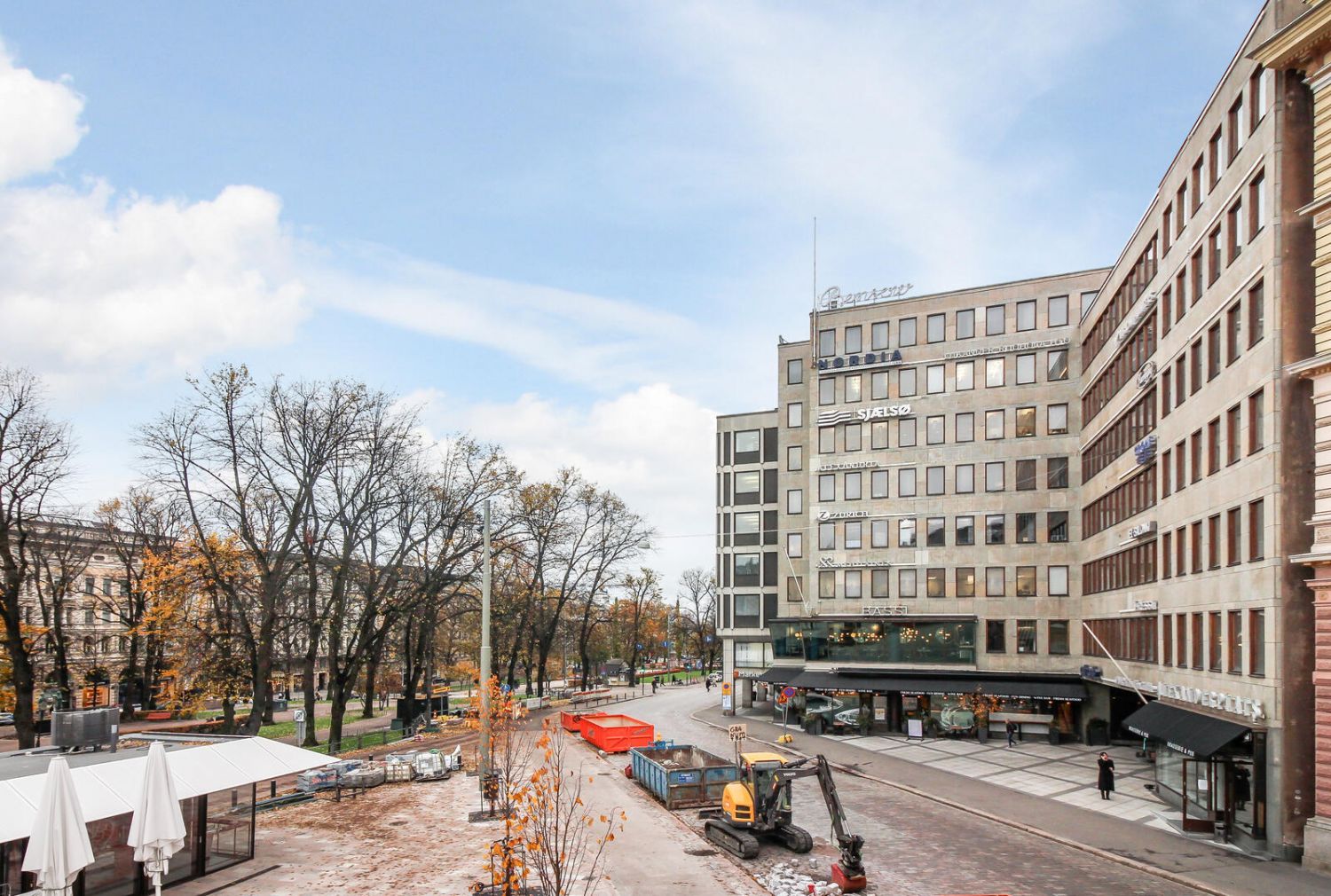 Näkymä kaupungin kadulta, jossa on rakennustyömaa ja toimistorakennuksia.