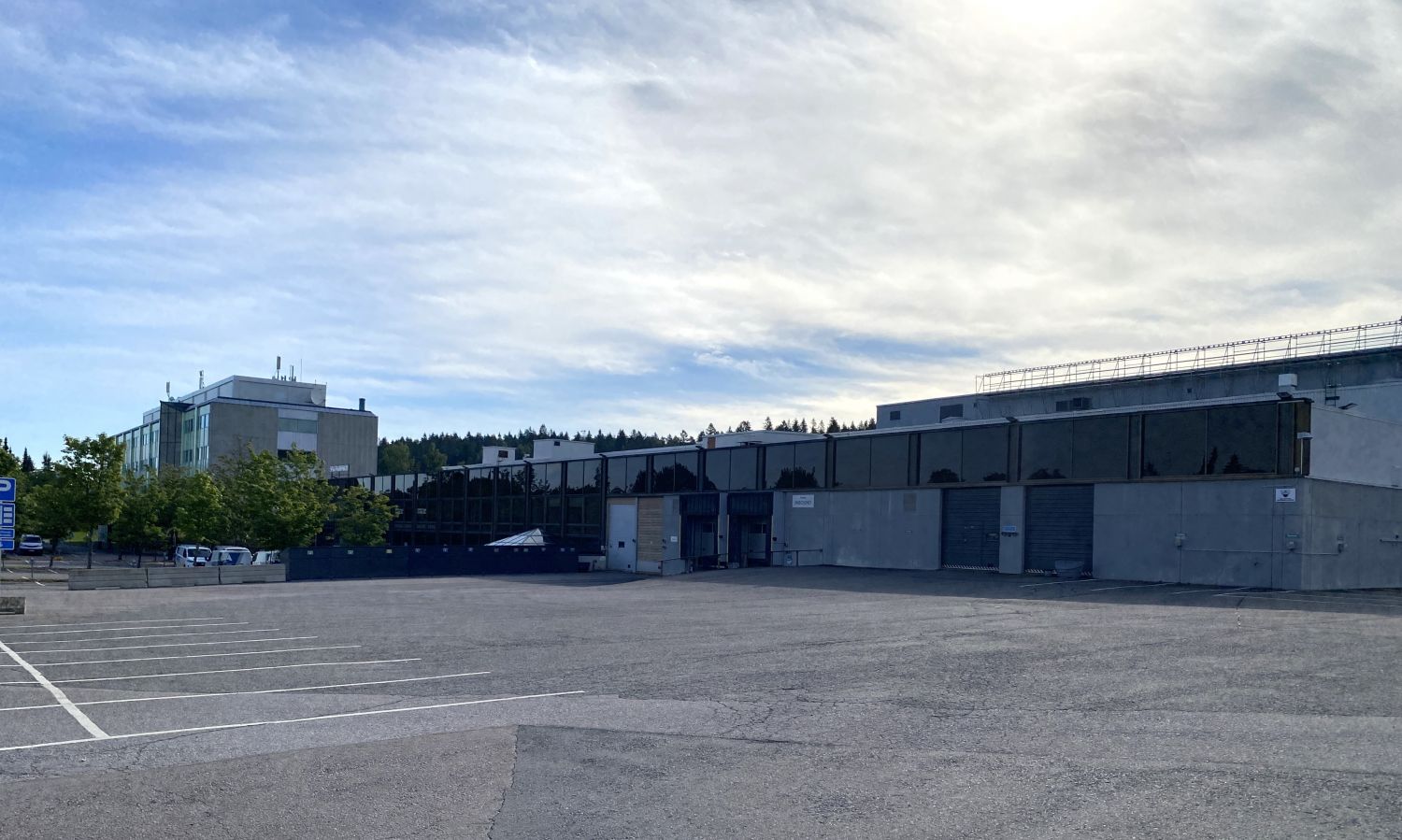 Teollisuusrakennus ja tyhjä pysäköintialue päivänvalossa.