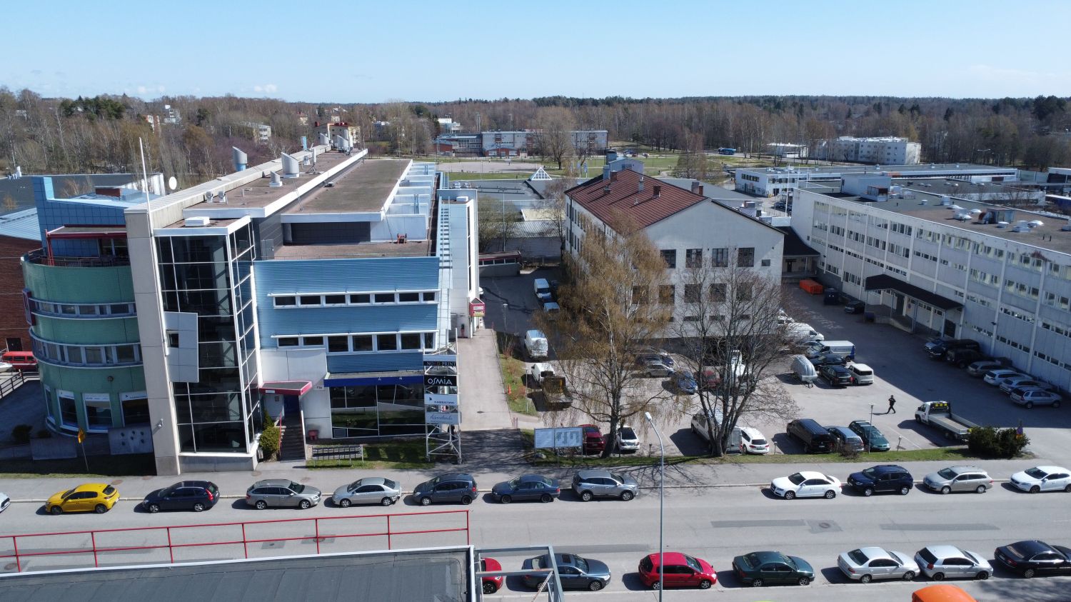 Ilmakuva liike- ja teollisuusalueesta rakennuksineen ja parkkipaikkoineen aurinkoisena päivänä.
